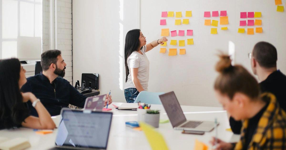 Equipo de marketing planificando temas de contenido sobre una mesa con laptops y notas