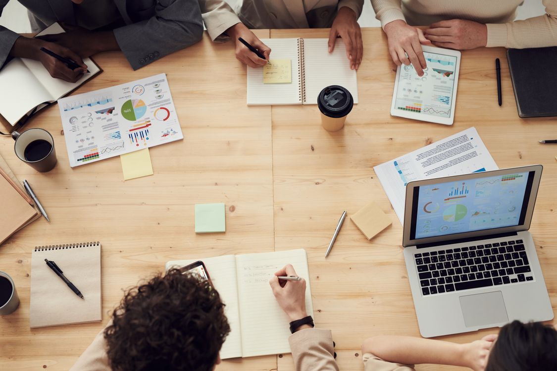 Equipo de profesionales reunidos en una mesa de trabajo revisando gráficos y documentos de planificación